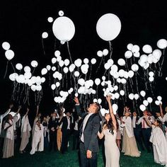 a bride and groom are surrounded by white balloons