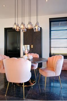 an elegant dining room with pink chairs and chandelier