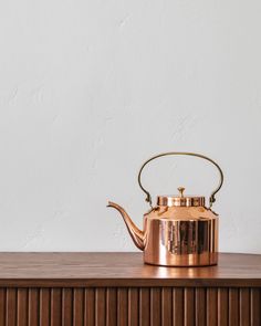 a copper tea kettle sitting on top of a wooden table