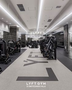 an empty gym with rows of machines and treadmills on the floor in black and white