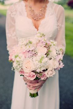 a woman holding a bouquet of white and pink flowers