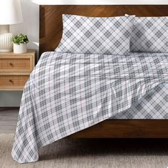 a bed with plaid sheets and pillows on it