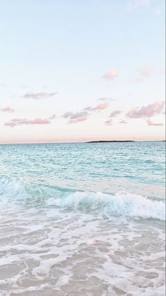 an ocean view with waves crashing on the shore and pink clouds in the sky above