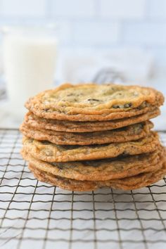 a stack of cookies sitting on top of a cooling rack next to a glass of milk