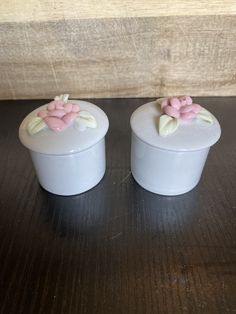 two small white containers with pink flowers on them