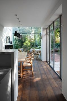 a dining room table and chairs in front of large windows with glass doors on both sides