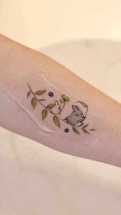 a small tattoo on the arm of a woman's arm with an animal and leaves design