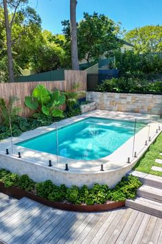 a swimming pool surrounded by wooden steps and greenery in the middle of a backyard