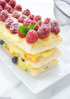 a white plate topped with dessert covered in raspberries