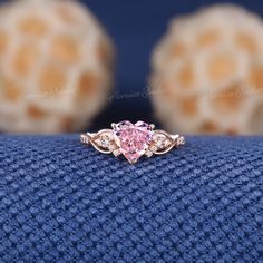 a pink diamond ring sitting on top of a blue cloth