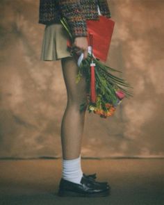 a woman in short skirt holding flowers and umbrella