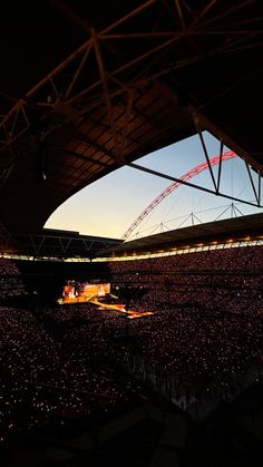 a large stadium filled with lots of people watching the sun set on top of it