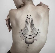 a woman's back with an abstract tattoo design on her left side ribcage