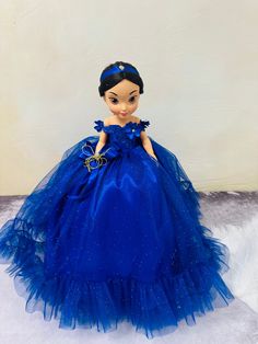 a doll in a blue dress sitting on top of a white furnishing floor