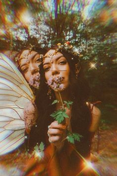 two women with wings and flowers in their hands, one holding a flower while the other holds