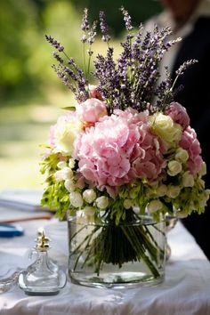 a vase filled with pink and white flowers sitting on top of a table next to two glasses