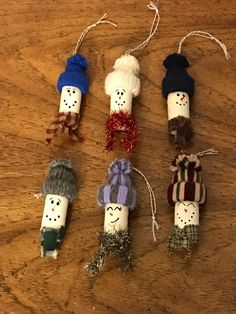 four snowmen made out of toilet rolls on a wooden table with string attached to them