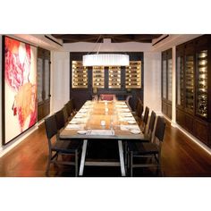 a dining room with a large wooden table surrounded by chairs and wine glasses on the wall