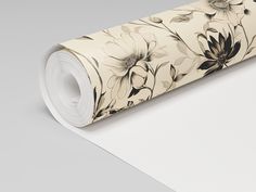 a roll of white paper with black and beige flowers on the bottom, sitting on top of a table