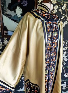 A gorgeous Chinese silk embroidery kimono robe, dating to the late 1940s. This is a great gold colour, eddging towards chartreuse in certain lights. It is lined in the same colour, but in rayon. It fastens with round brass buttons, has wide long sleeves and side vents. Edged in silk bands with fine silk embroidery of butterflies and flowers. Original label reads Dunhuang, Made in China. Nape to hem 36.5" Chest 46" Condition wise, the odd fine brushing to the silk and very faint marks only visibl Vintage Kimono With Floral Embroidery, Ceremonial Vintage Kimono, Traditional Embroidered Silk Kimono, Traditional Embroidered Kimono For Tea Ceremony, Chinese Silk Embroidery, Embroidery Kimono, Embroidered Robes, Dunhuang, Embroidered Kimono