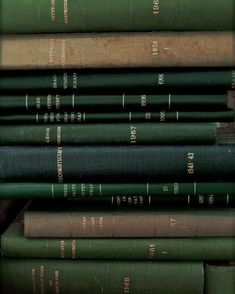 a stack of green books sitting next to each other on top of a wooden table