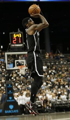 a basketball player jumping up to dunk the ball in front of an arena full of people