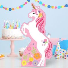 there is a pink unicorn cake with candles on it and other decorations around the table