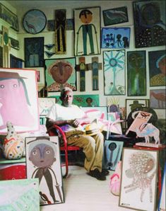 a man sitting in a chair surrounded by paintings