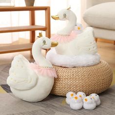 three white ducks sitting on top of a basket next to two baby ducklings in it