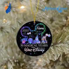 a christmas ornament hanging on a tree with the disney castle in the background