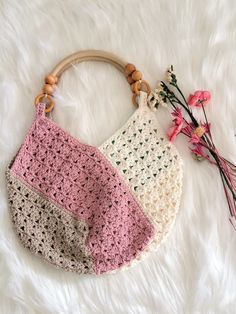 two crocheted purses sitting on top of a white furnishing next to flowers