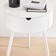 a white table with two books and a black vase on the top, next to it