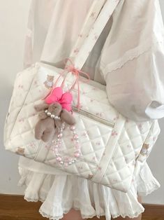 a woman holding a white purse with a pink bow on it's handle and a teddy bear in the pocket