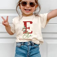 Custom Kids Elf Christmas Name Shirt for Boys and Girls, Toddler Xmas Tee Kindergarten Christmas Shirt With Name, Toddler Holiday Sweatshirt 🌸 Soft & Lightweight Material - Graphic tees for women are made from a soft, lightweight, and stretchy fabric that provides a familiar and comfortable feel. You'll love wearing it all day long. 🌸 GREAT GIFT:  Good choice as a gift for your mom, sister, your wife or anyone you want to send a gift.  🌸 Wash: Recommended machine/hand wash and wash inside out and line dry. PLEASE DON'T Put IT IN THE DRYER, DRY CLEAN, or BLEACH. ♥️Designed and Handmade in the USA♥️ Kindergarten Christmas, Holidays With Toddlers, Christmas Kindergarten, Christmas Names, Xmas Tees, Shirt For Boys, Custom Kids, Elf Christmas, Christmas Tops