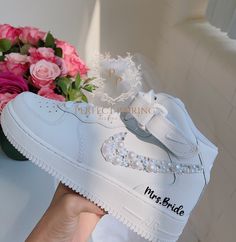 a pair of white shoes with pearls on the soles and flowers next to it