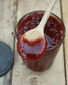 a wooden spoon in a jar filled with ketchup on top of a table