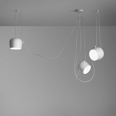 three white lamps hanging from the ceiling in a room with gray walls and flooring