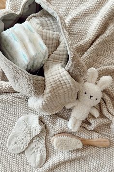 a baby's diaper and its contents are laid out on the bed, including a teddy bear