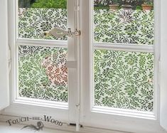 an open window with green and white wallpaper on the outside, in front of a tree