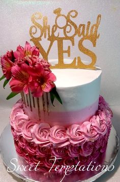 a pink and white cake with flowers on the top is decorated with gold letters that say sweet yes