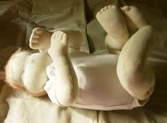 a teddy bear laying on top of a bed next to a stuffed animal in the shape of a baby