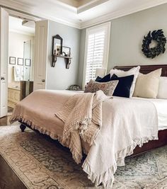 a large bed sitting in the middle of a bedroom next to a window with shutters