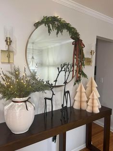 a mirror sitting on top of a wooden table next to a vase filled with plants