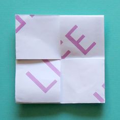 an origami piece with pink lines on it sitting on top of a blue surface