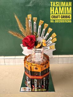 a basket filled with chocolate bars and a red rose sitting on top of the box