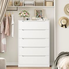 a white dresser sitting next to a bed in a bedroom