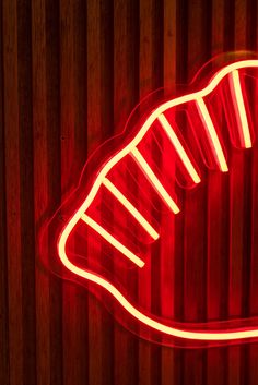 a red neon sign on the side of a wooden wall