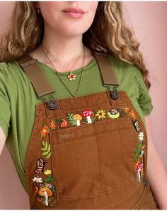 a woman with long hair wearing overalls and a green t - shirt is posing for the camera