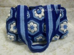 a crocheted blue and white purse with flowers on it