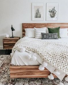 a bed with white blankets and pillows in a room next to two pictures on the wall